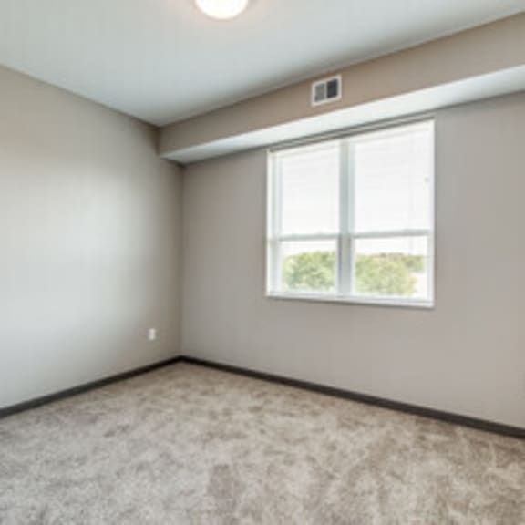 an empty room with a window and carpet