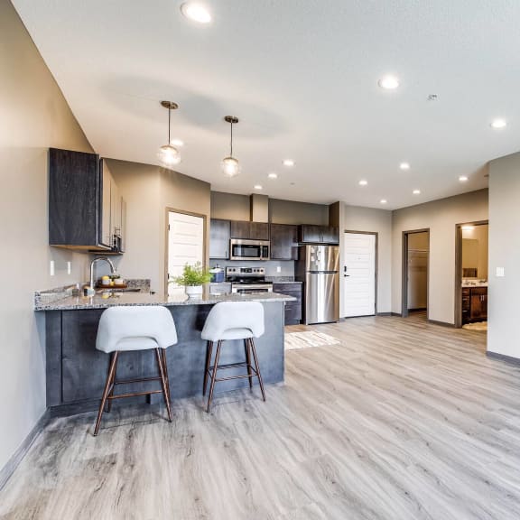 an open kitchen and living room with a kitchen island and bar stools