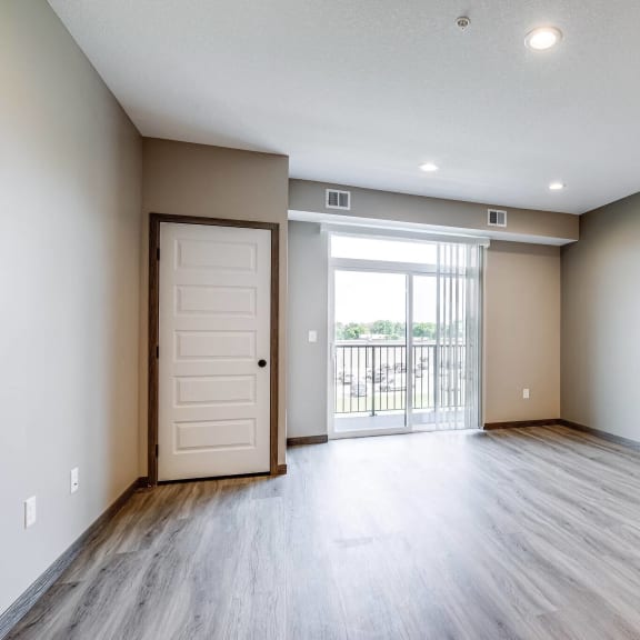 an empty living room with a door to a balcony