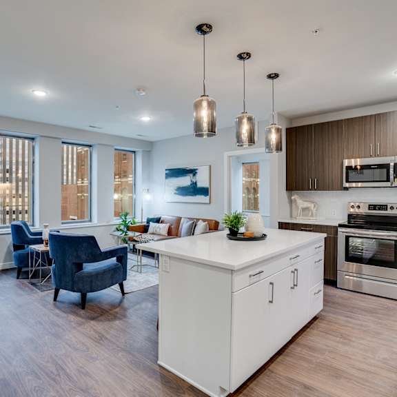 a modern kitchen with a white island and wooden floors.