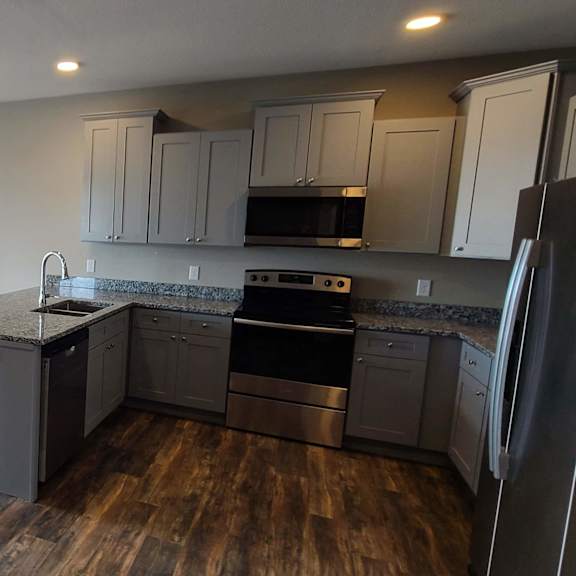 a kitchen and living room with wood floors and stainless steel appliances