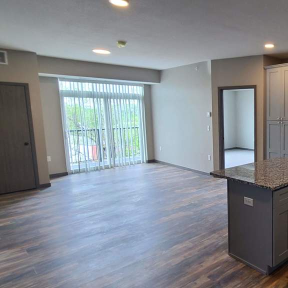an empty kitchen and living room with a door to a balcony