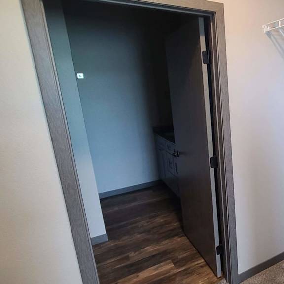 a walk in closet with a white wall and a closet door open