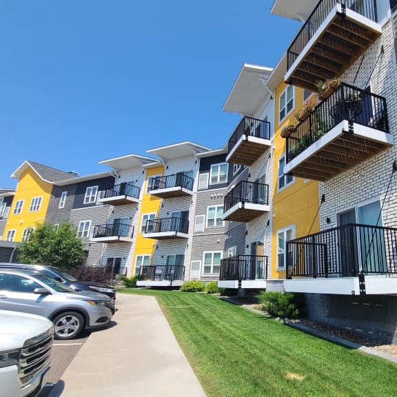 a row of apartments with balconies and cars parked in front