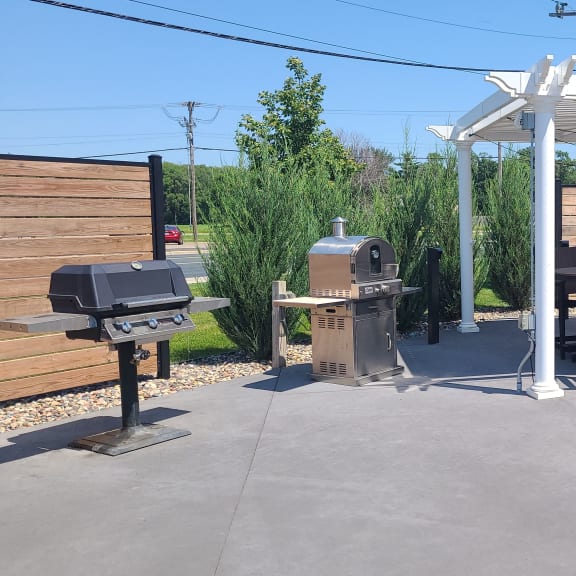 a patio with a grill and a table and chairs under a white canopy