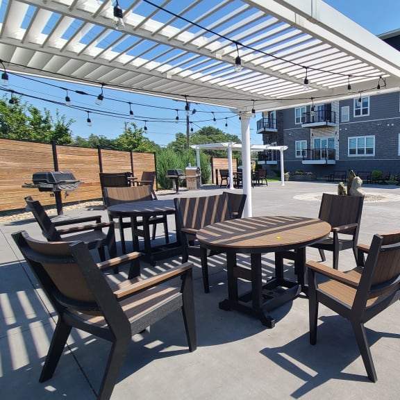 an outdoor patio with tables and chairs under a white canopy