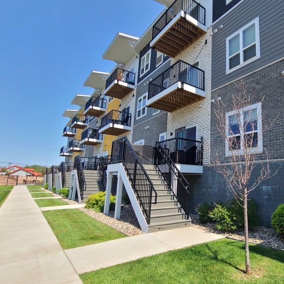 an exterior view of an apartment building with grass and a sidewalk