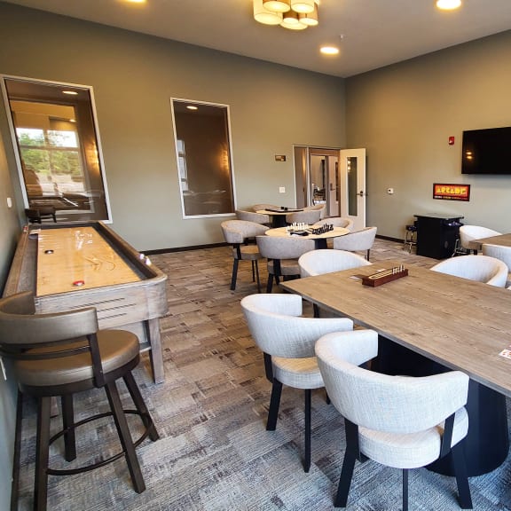 a game room with tables and chairs and a shuffleboard