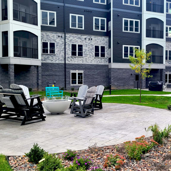 an outdoor patio with chairs and a table in front of an apartment building