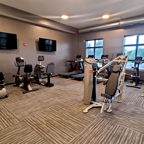 a gym with treadmills and other exercise equipment in a building with large windows