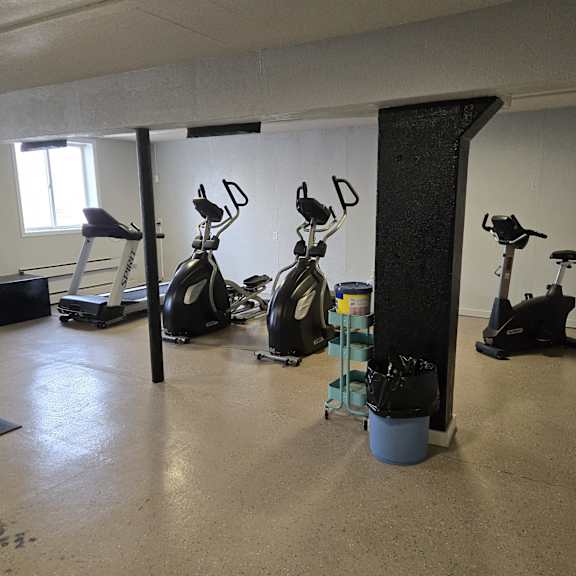 a room with exercise equipment and a blue barrel.