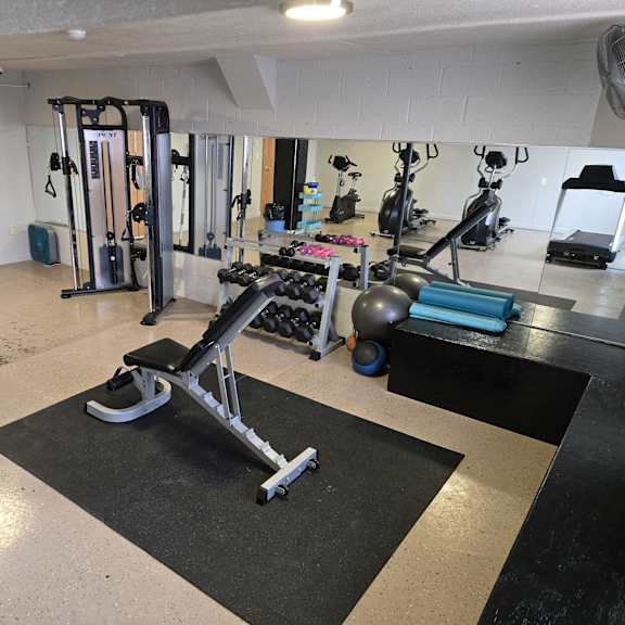 a gym with a variety of equipment including a rowing machine.