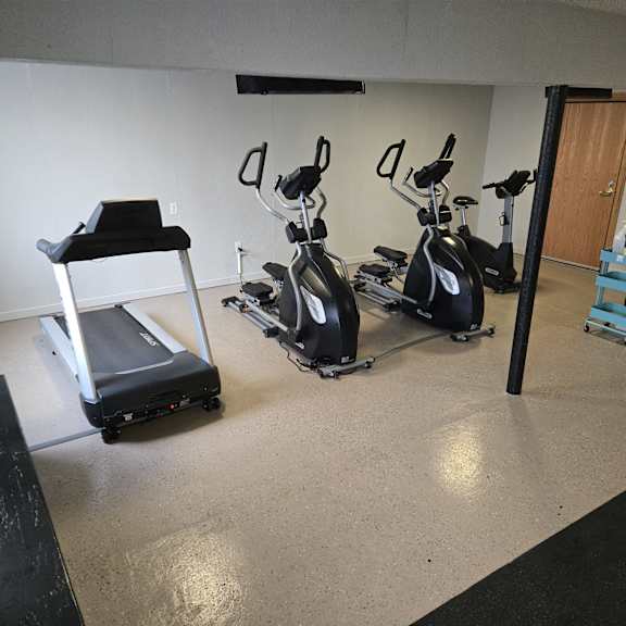 a room with exercise equipment and a black bench.