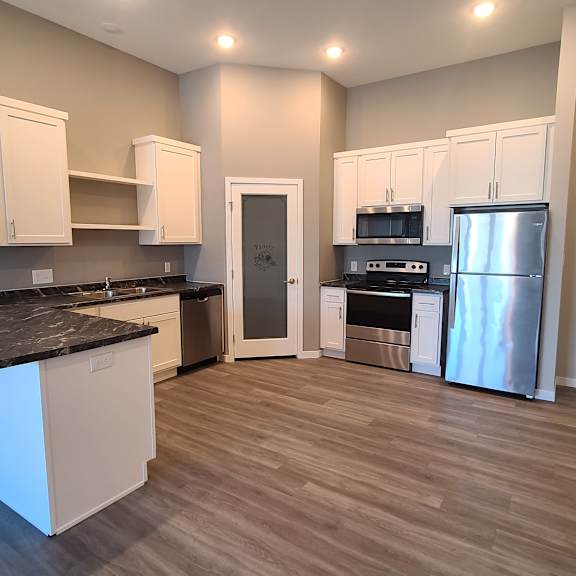 a kitchen with white cabinets and a black countertop.