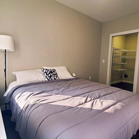 a bedroom with a bed, nightstand, and lamp.