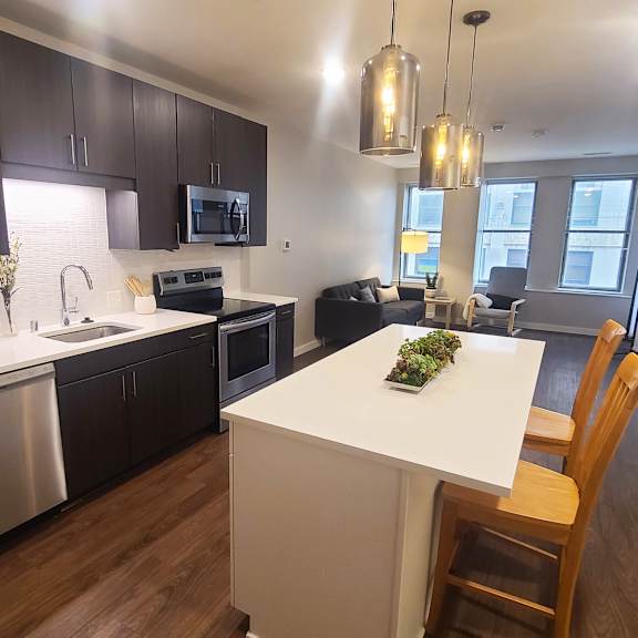 a modern kitchen with a white island and wooden chairs.