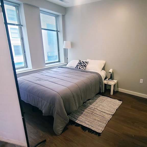 a bedroom with a bed, nightstand, and window.