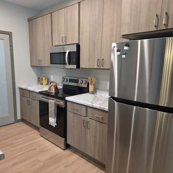 a modern kitchen with a stainless steel refrigerator, microwave, and oven.