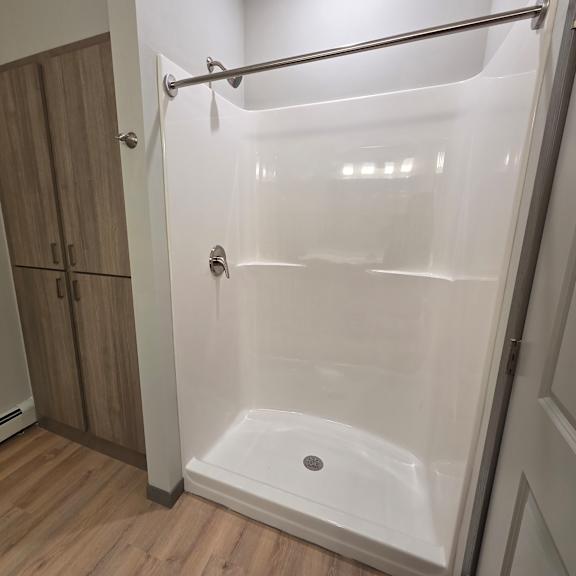 a white shower stall with a door and a shower head.