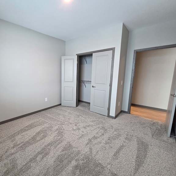 a room with grey carpet and a grey wall with a white door and a grey wardrobe.