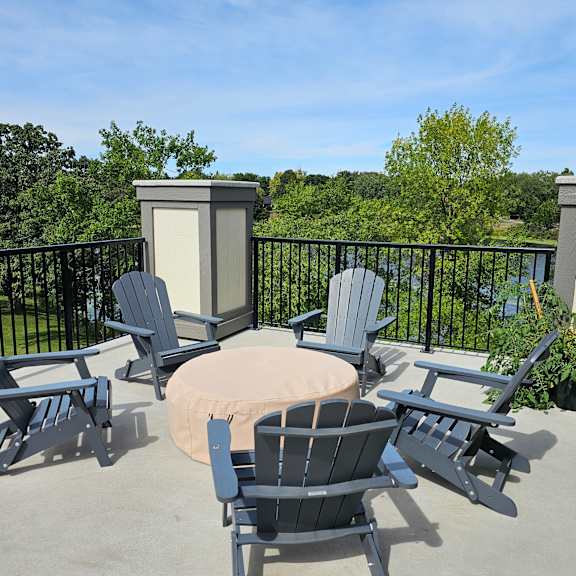 a patio with a table surrounded by chairs and a black railing.
