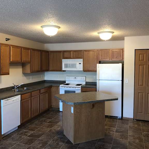 a kitchen with brown cabinets and a white fridge.