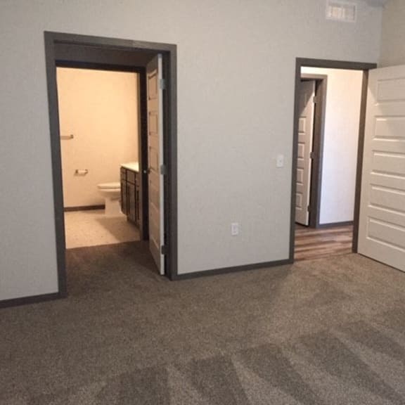 an empty living room with a door open to a bathroom
