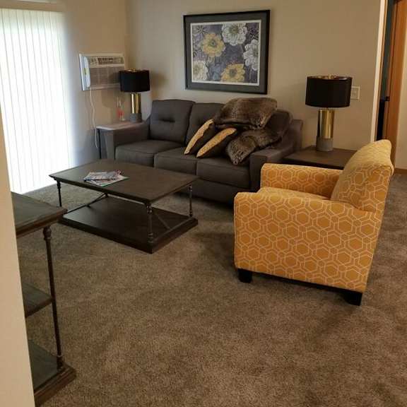 a living room with a grey couch, a yellow chair, and a coffee table.
