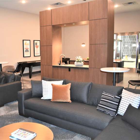 a living room with black couches and a wooden mirror.