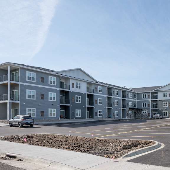 an exterior view of an apartment building with a parking lot