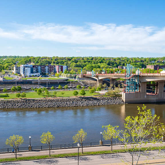 a bridge over a river with trees and buildings in the background.