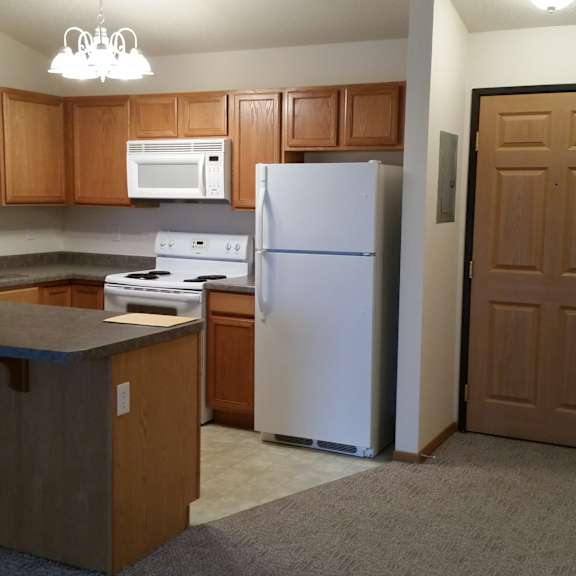 a kitchen with a white refrigerator and a white microwave above the stove.