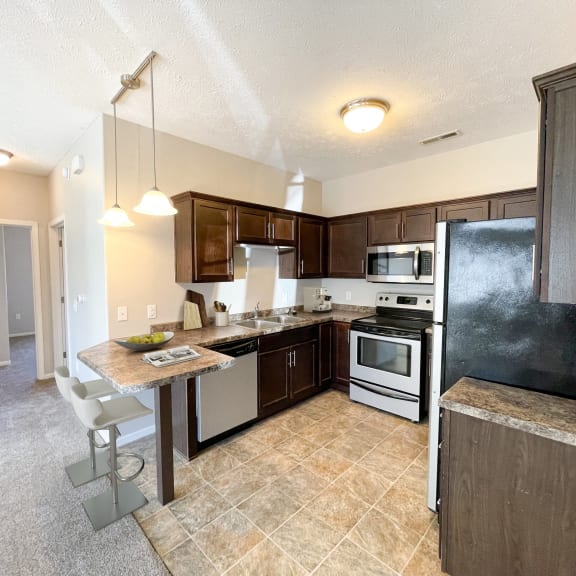 a kitchen with stainless steel appliances and a bar with a counter top