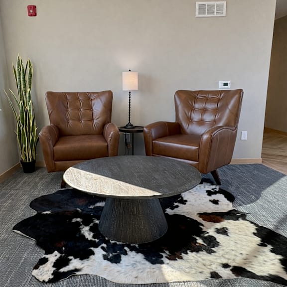 a living room with two leather chairs, a table, and a cowhide rug.