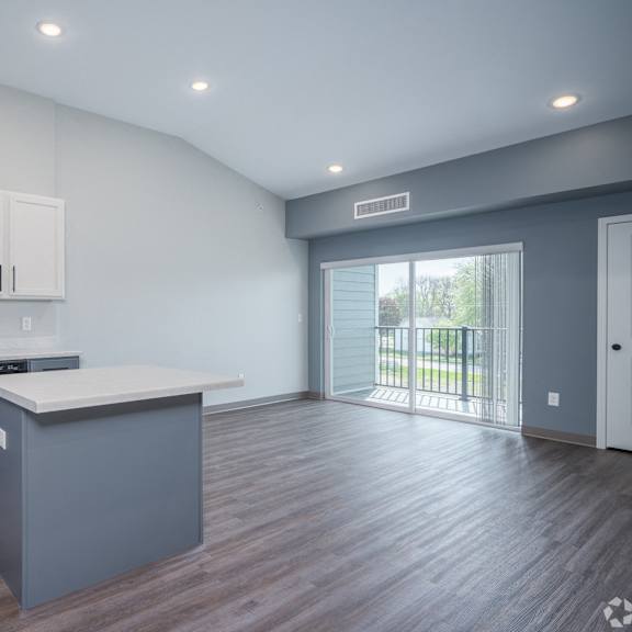 an empty kitchen and living room with a door to a balcony