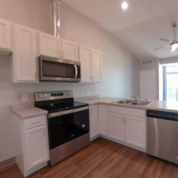 an empty kitchen with white cabinets and stainless steel appliances