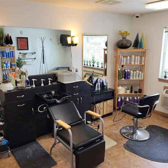 a hair salon with black chairs and a mirror.