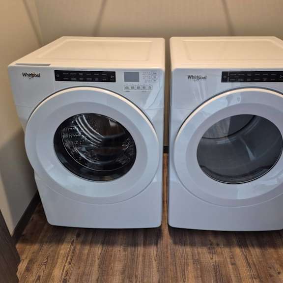 two white whirlpool washing machines in a small room.