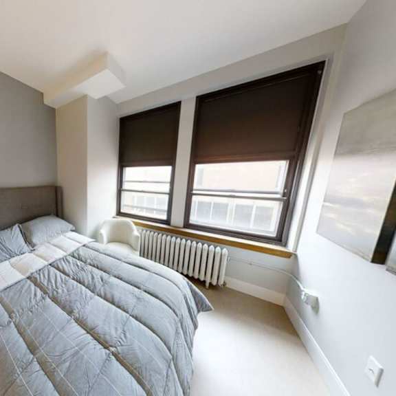 a bedroom with a large bed and two windows