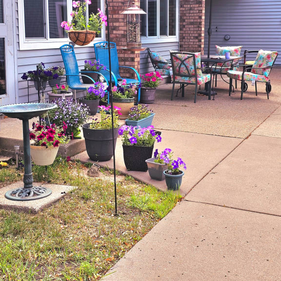 a patio with chairs and umbrellas and pots of flowers
