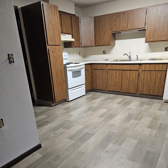 an empty kitchen with wooden cabinets and a stove and a sink