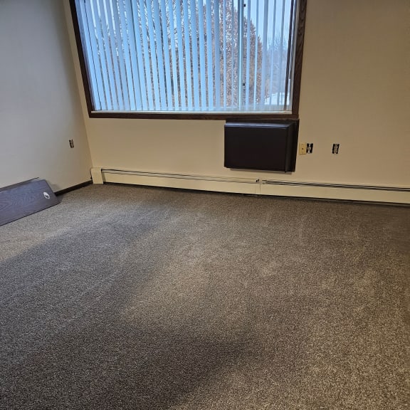 a room with a large window and a carpeted floor