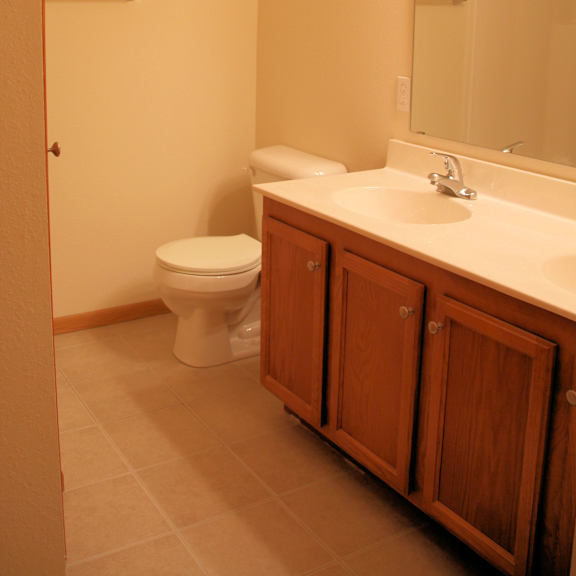 a bathroom with a toilet, sink and mirror.