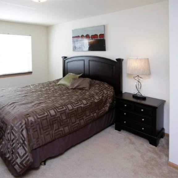 a bedroom with a bed, nightstand, and window.