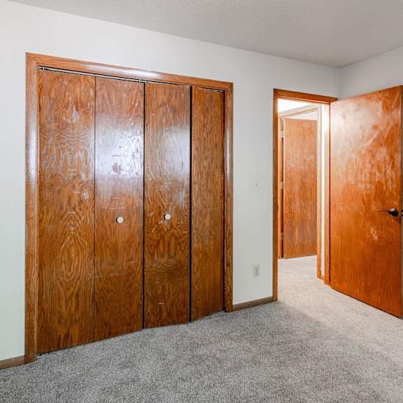 a room with a carpeted floor and two wooden doors.