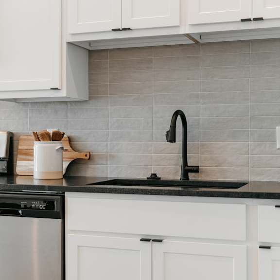a kitchen with white cabinets and a black dishwasher.