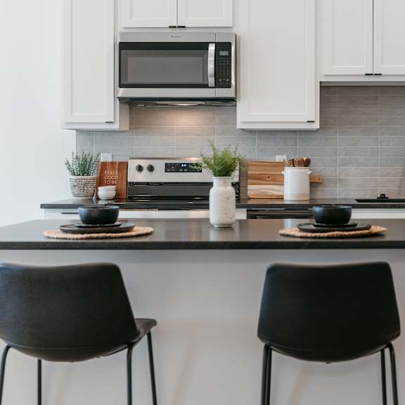two black chairs are placed in front of a kitchen island.