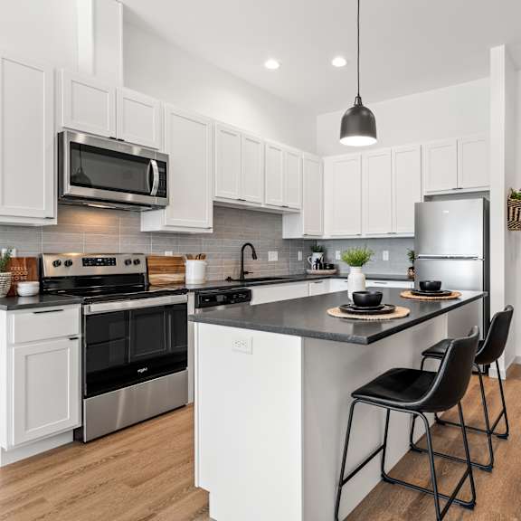 a modern kitchen with white cabinets and black countertops.