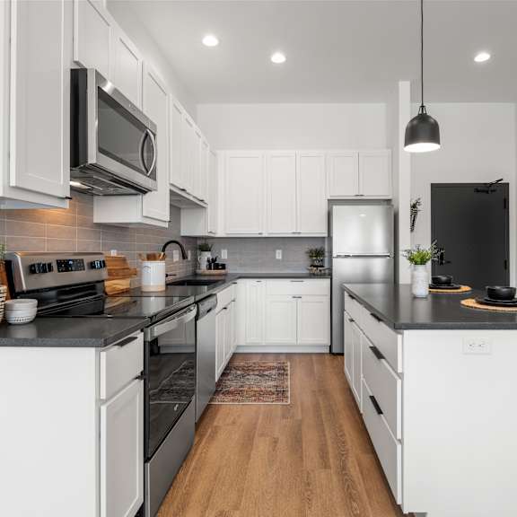 a modern kitchen with white cabinets and black countertops.