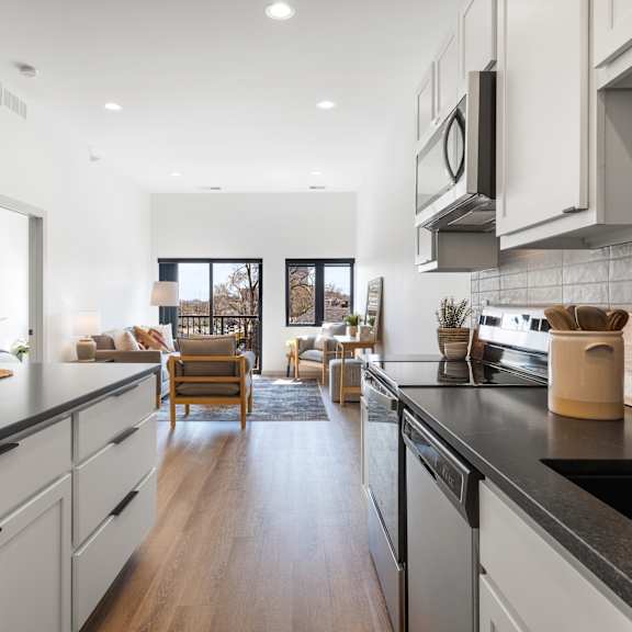 a modern kitchen with a black countertop and white cabinets.